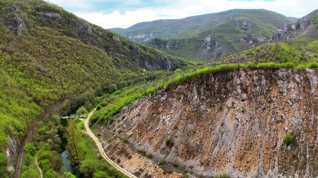 Aerial 4K Drone Low Flight View Along Rocky Limestone Cliff Face of Zemen Gorge in Bulgaria