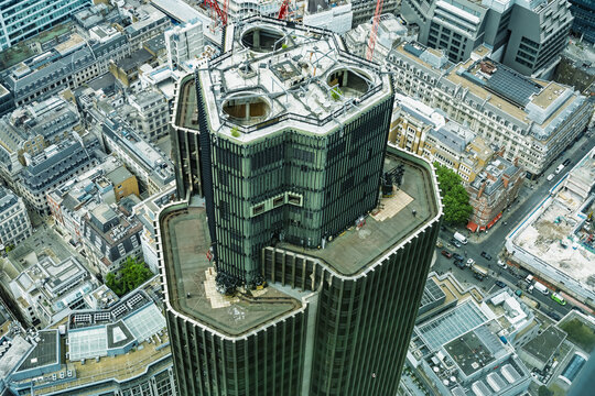 View of the distinctive geometric architecture of Tower 42 surrounded by the dense urban grid of streets and buildings in London, England, United Kingdom.