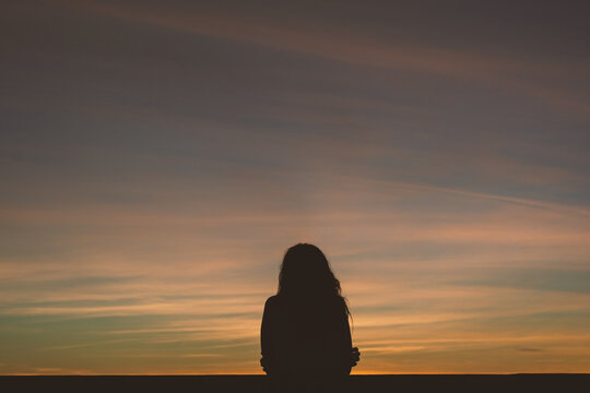 Person observing the sea from the balustrade at sunset