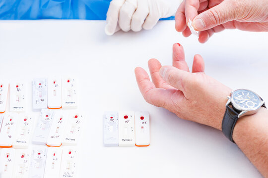 Senior patient holding cotton swab after blood test near rapid express diagnostic cassettes