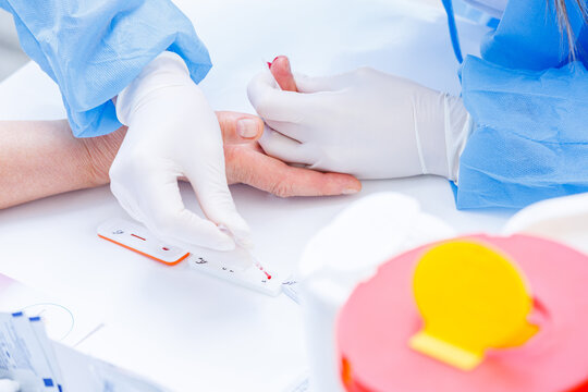 Doctor applying blood sample with pipette onto rapid test cassette for diagnostic