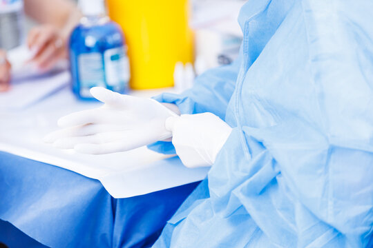 Doctor pulling on white sterile gloves for infection control safety protocol