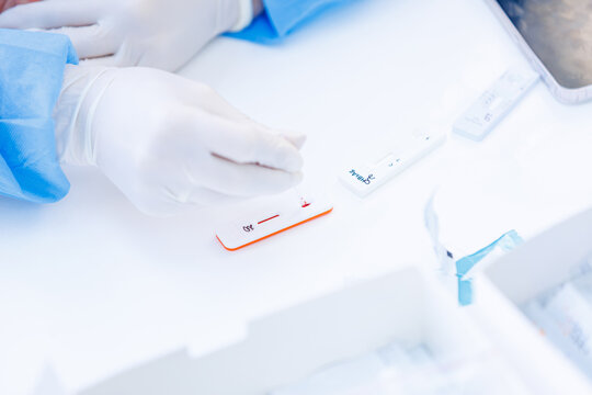 Doctor applying blood sample with capillary tube onto rapid express test cassette