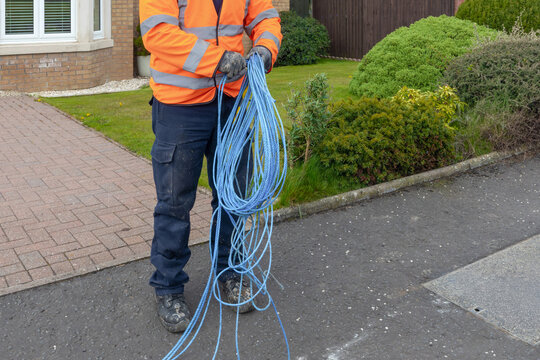 Engineer coiling blue draw rope by hand at residential street works