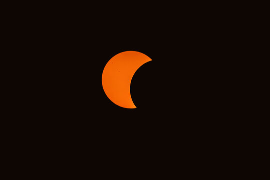 Partial solar eclipse with crescent shaped sun against a dark sky