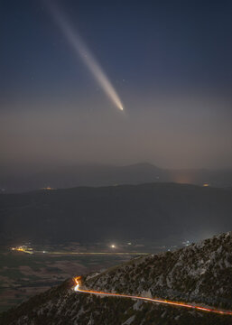 View of the comet Tsuchinshan-ATLAS shining in the night sky above the winding road and mountainous landscape of the Castelluccio plateau in Castelluccio, Umbria, Italy.