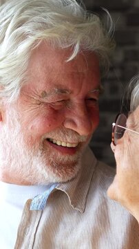Happy senior couple showing affection and love as the smiling woman gives her husband an eskimo kiss, rubbing noses together in a tender display of their lasting romantic relationship