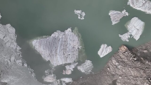 Aerial Top Down View of Calving Glacier with Floating Ice Chunks in Turquoise Glacial Lake Switzerland