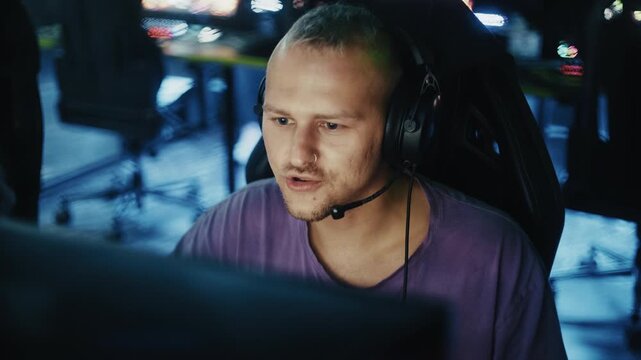 Young man with headset playing video games in a dark computer club during a cybersport tournament