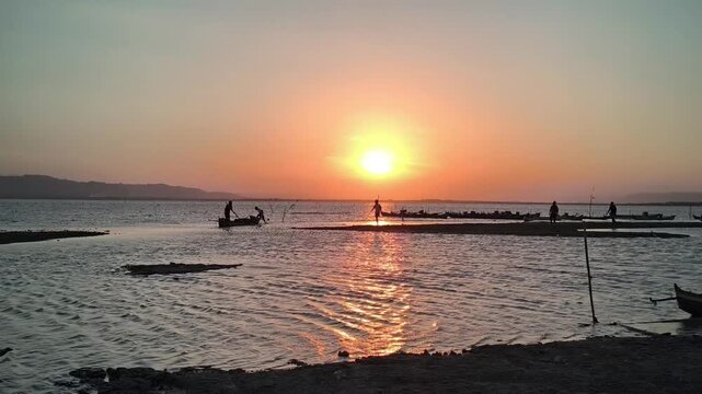 Golden Sunset over Calm Water with Silhouetted Fishermen and Boats