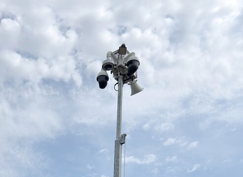Solar powered mobile security camera trailer with dome cameras, megaphones, solar panels operating in commercial parking lot for crime deterrence