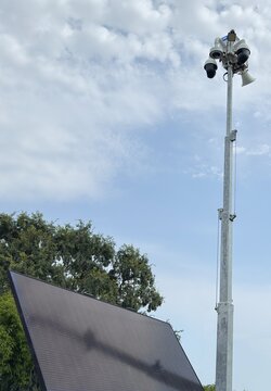 Solar powered mobile security camera trailer with dome cameras, megaphones, solar panels operating in commercial parking lot for crime deterrence