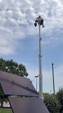 Solar powered mobile security camera trailer with dome cameras, megaphones, solar panels operating in commercial parking lot for crime deterrence