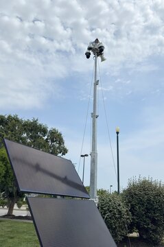 Solar powered mobile security camera trailer with dome cameras, megaphones, solar panels operating in commercial parking lot for crime deterrence