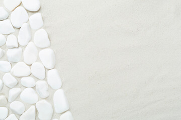White pebble stones with sand as background, top view © Liami