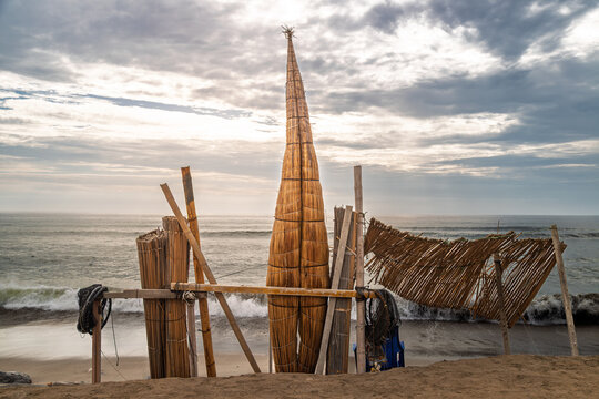 Traditional Peruvian reed boat (caballito de totora) on a sandy beach with the Pacific Ocean in Huanchaco, near Trujillo, Peru