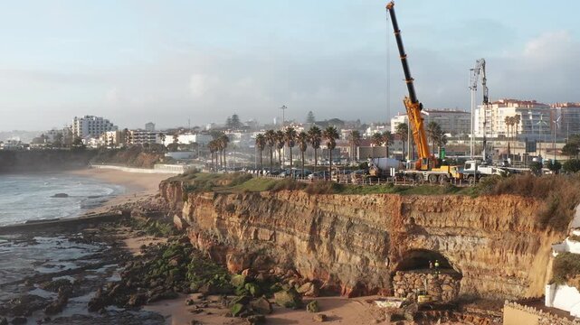 Work is ongoing at Sao Pedro Do Estoril aerial view beach to tackle the issue of soil erosion. Heavy equipment is used to stabilize the area and protect the coastline from further damage.