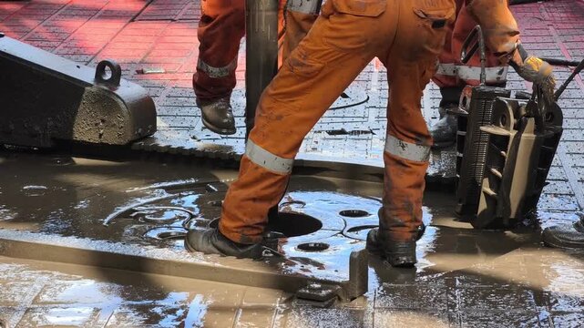 Rig crew perform pulling of of hole drill string with oil based mud on the rig floor. Trip out of hole.