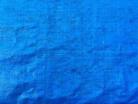 Full frame macro texture of a blue woven plastic tarp sheet.