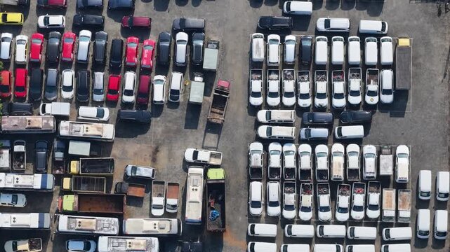 Large parking area filled with various vehicles parked in organized rows under bright daylight