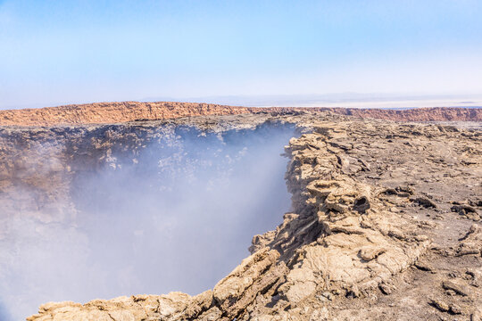 View of Erta Ale volcano crater with rising steam and rugged lava rock formations, Afar Region, Ethiopia.