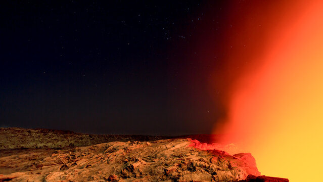 View of the glowing lava lake at Erta Ale volcano under a starry night sky.