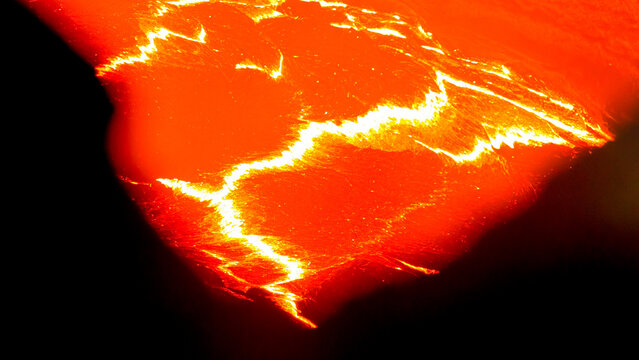 View of molten lava flowing from a volcanic vent with glowing cracks and intense heat.