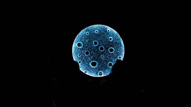 View of a glowing moon-like art installation with crater details illuminated in the dark at the Oregon Country Fair in Veneta, Oregon, United States.