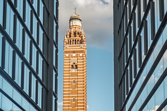 View of Westminster Cathedral campanile framed by modern glass skyscrapers under a blue sky in London, England, United Kingdom.