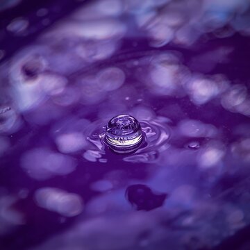 Vibrant Purple Water Droplet Creating Ripples with Bokeh