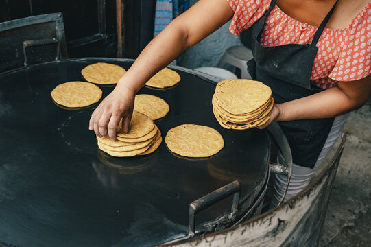 View of a person cooking fresh corn tortillas on a large black metal griddle in Antigua Guatemala, Sacatepequez Department, Guatemala.
