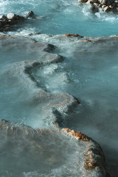 Aerial view of turquoise mineral-rich water flowing over natural limestone terraces at the thermal hot springs in Saturnia, Tuscany, Italy.