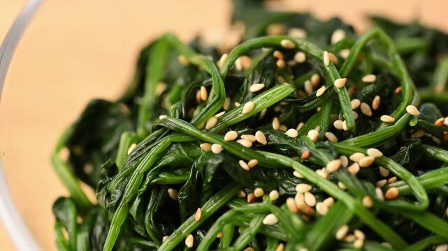 Close-up of Korean spinach salad (Segeumchi namul) in a bowl, sliding smooth pan
