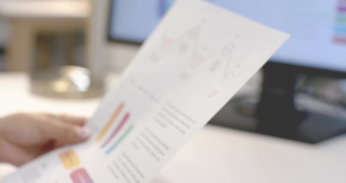Woman's hands reviewing report pages, pointing and tracing charts at desk, analyzing circled peak