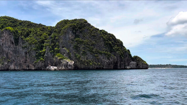 View of the limestone cliffs of Ko Phi Phi Lee rising from the turquoise sea under a bright sky in Ao Nang, Krabi, Thailand.