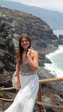 Happy young woman smiling on volcanic island coastline