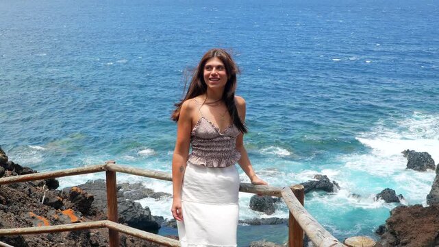 Happy young woman spreading arms on a volcanic coast
