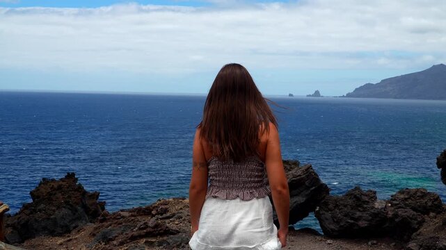 Free woman enjoying ocean view on a cliff