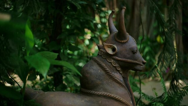 Handcrafted terracotta bull sculpture surrounded by green plants