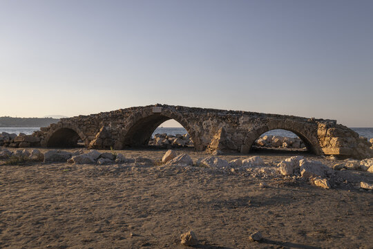 View of the historic old Venetian bridge with stone arches situated on the sandy beach by the sea in Argassi, Greece.