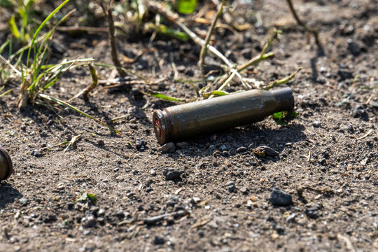 Empty spent bullet casing shell on dry ground dirt closeup macro texture background.
