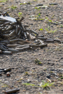 Empty spent bullet casing shell on dry ground dirt closeup macro texture background.
