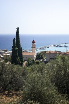 View of the church with a red dome overlooking the harbor with boats and blue sea in Zakinthos, Greece.