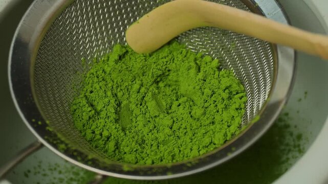 Matcha green tea is sift through a sieve.