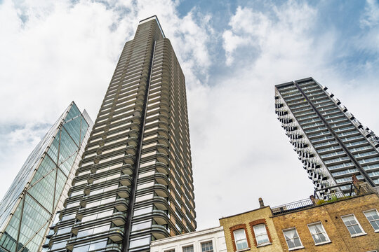 View of modern skyscrapers towering over historic brick buildings under a cloudy sky in the Liverpool Street area London, England, United Kingdom.