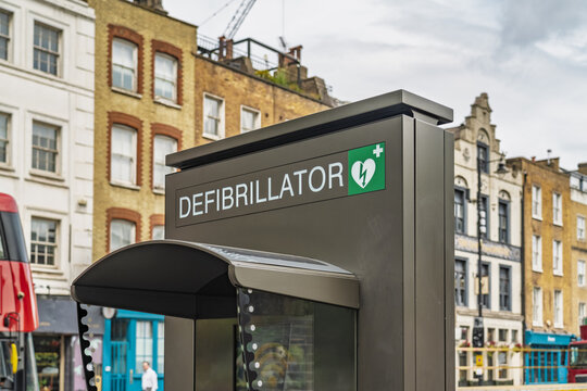 View of a modern public access defibrillator unit located near the historic Liverpool Street station with traditional brick architecture in the background London, England, United Kingdom.