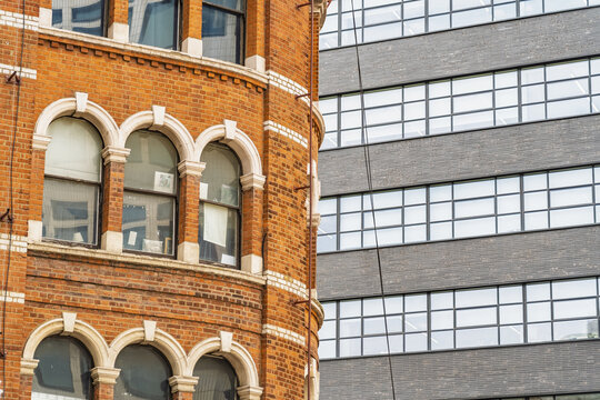 View of the historic red brick architecture of Shoreditch contrasting with a modern dark grey office building in London, England, United Kingdom.