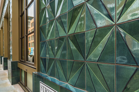 View of the geometric green ceramic tile facade at Liverpool Street, featuring sharp angular patterns and reflective surfaces in London, England, United Kingdom.