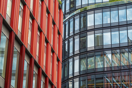 View of modern glass office buildings with striking red facade elements and reflective windows near Liverpool Street in London, England, United Kingdom.
