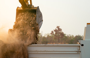 Backhoe loading soil into heavy duty dump truck at construction site. Crawler excavator transporting dirt with powerful bucket. Heavy construction machinery. Industrial earthmoving equipment in action © Fahroni
